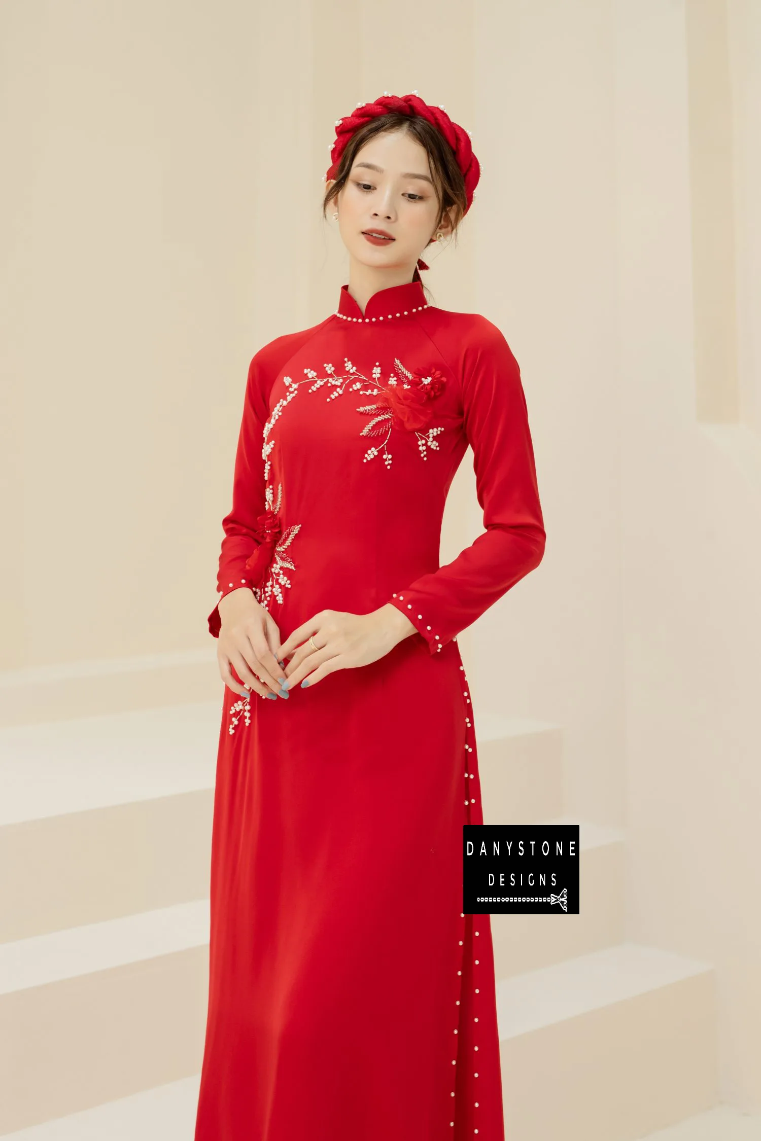 Woman in a red silk Áo Dài, featuring intricate jade flower patterns and pearl details.