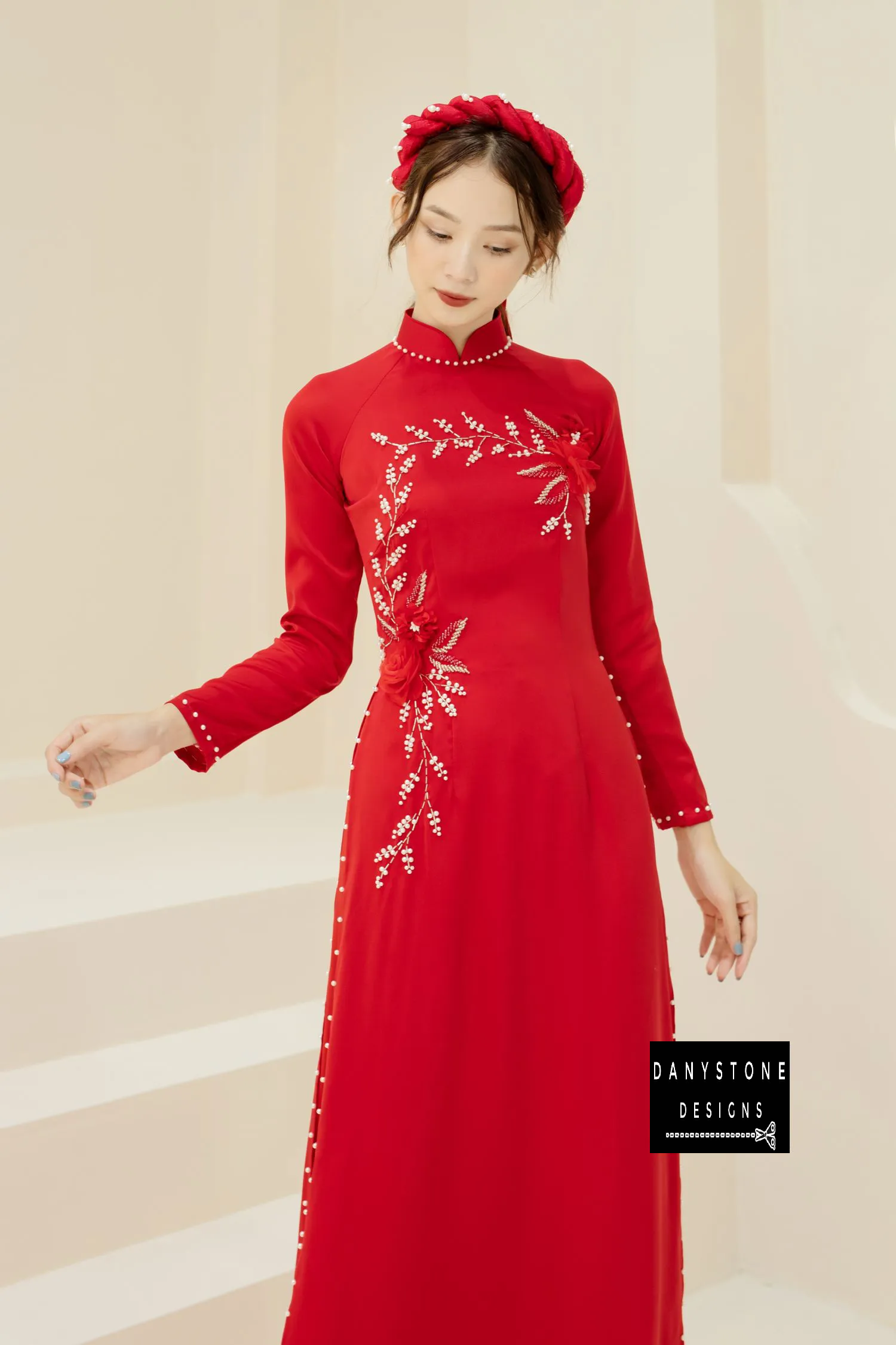 Side view of a red silk bridal Áo Dài with delicate jade flowers and pearl branches.