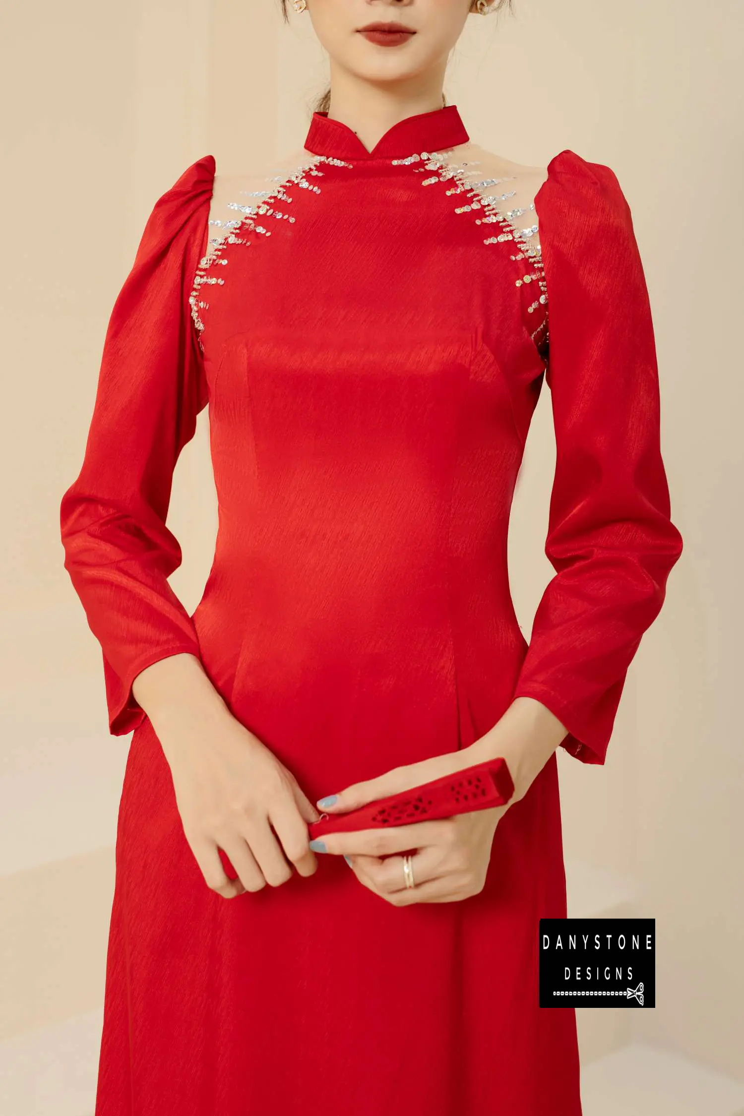 Full-length view of a bride wearing a red silk Áo Dài with shrug sleeves and intricate beadwork.