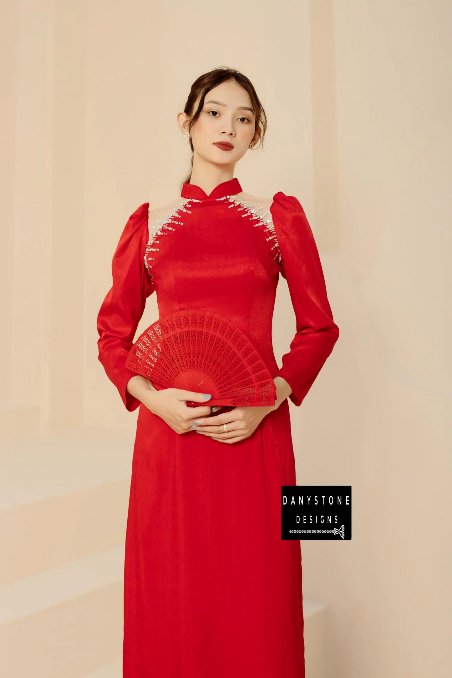 Elegant woman in a red silk bridal Áo Dài with shrug sleeves and beaded details.