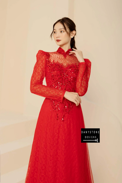 Full-length view of a bride in a red beaded lace Áo Dài with a flowing skirt.