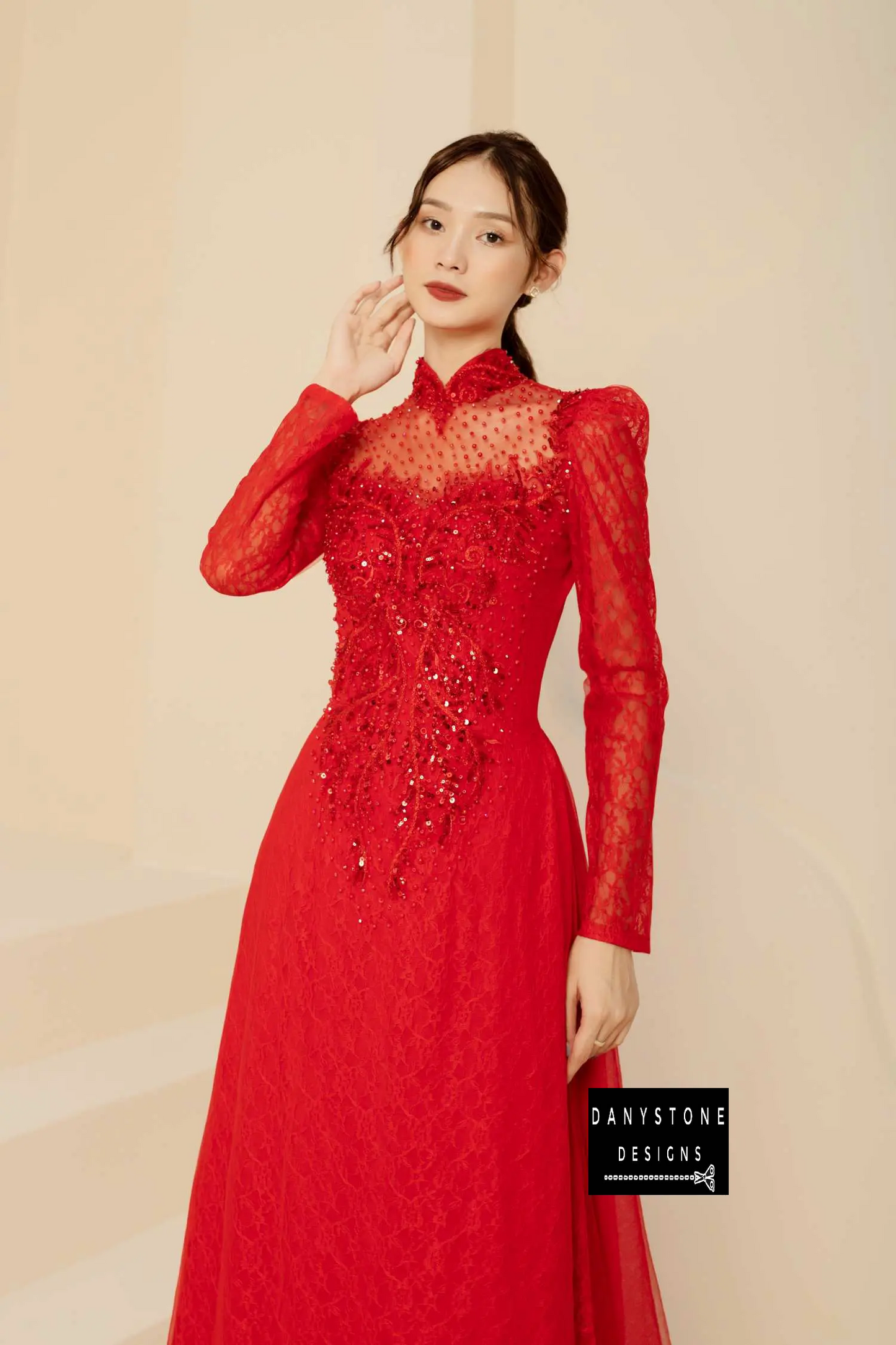  Woman in a red lace Áo Dài with a long standing collar and intricate beaded details.