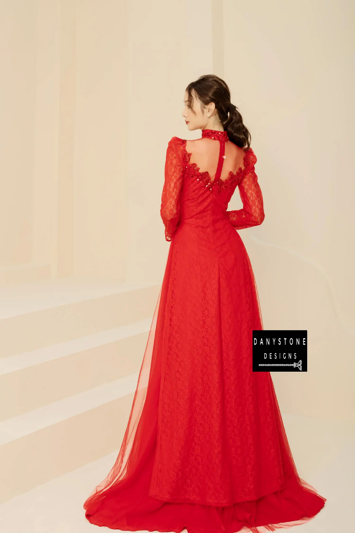 Side view of a red beaded lace bridal gown with puffed sleeves and a flowing skirt.