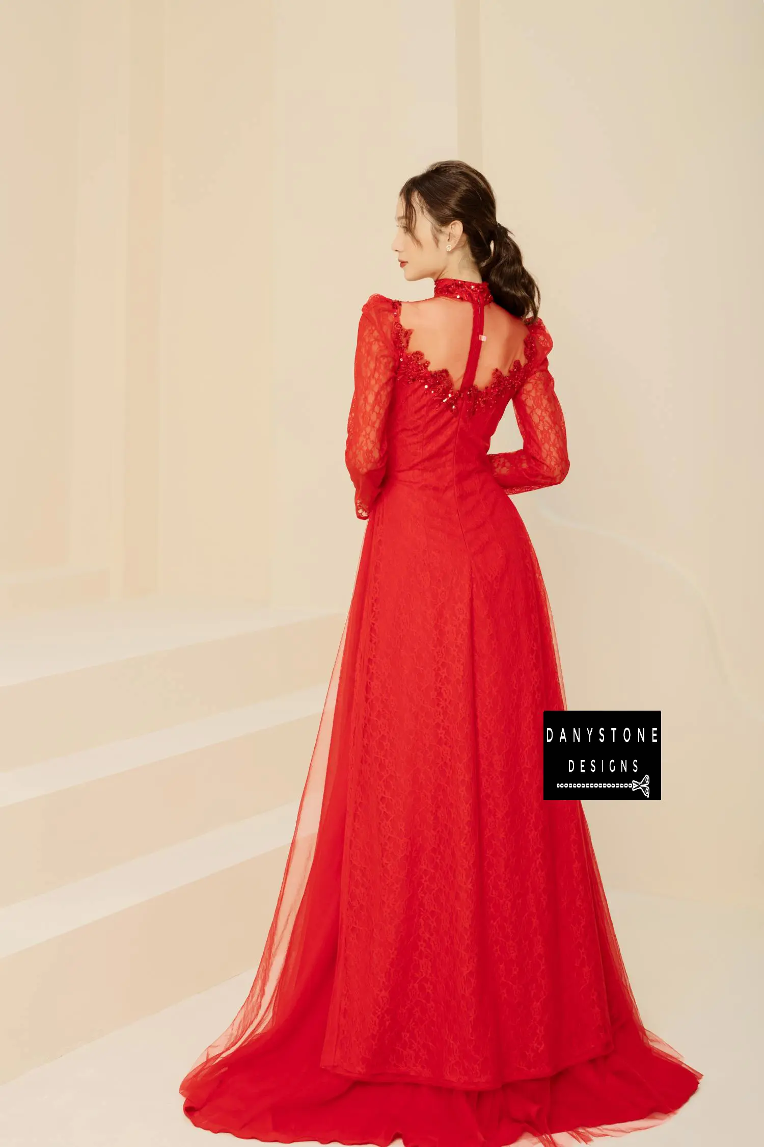 Side view of a red beaded lace bridal gown with puffed sleeves and a flowing skirt.