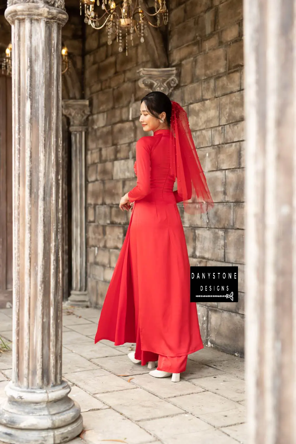 Full-length view of a bride wearing a red silk Áo Dài with intricate beaded details.