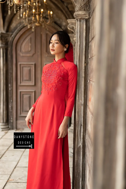 Red silk Áo Dài with luxurious beaded flowers and joy symbol, worn by a bride.