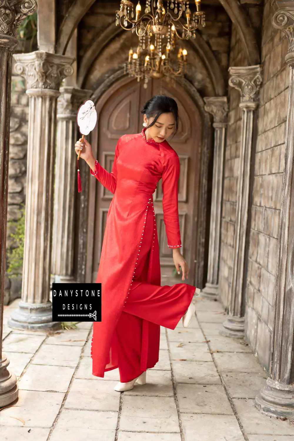 Red brocade Áo Dài with luxurious beaded collar and pearl details, worn by a bride.