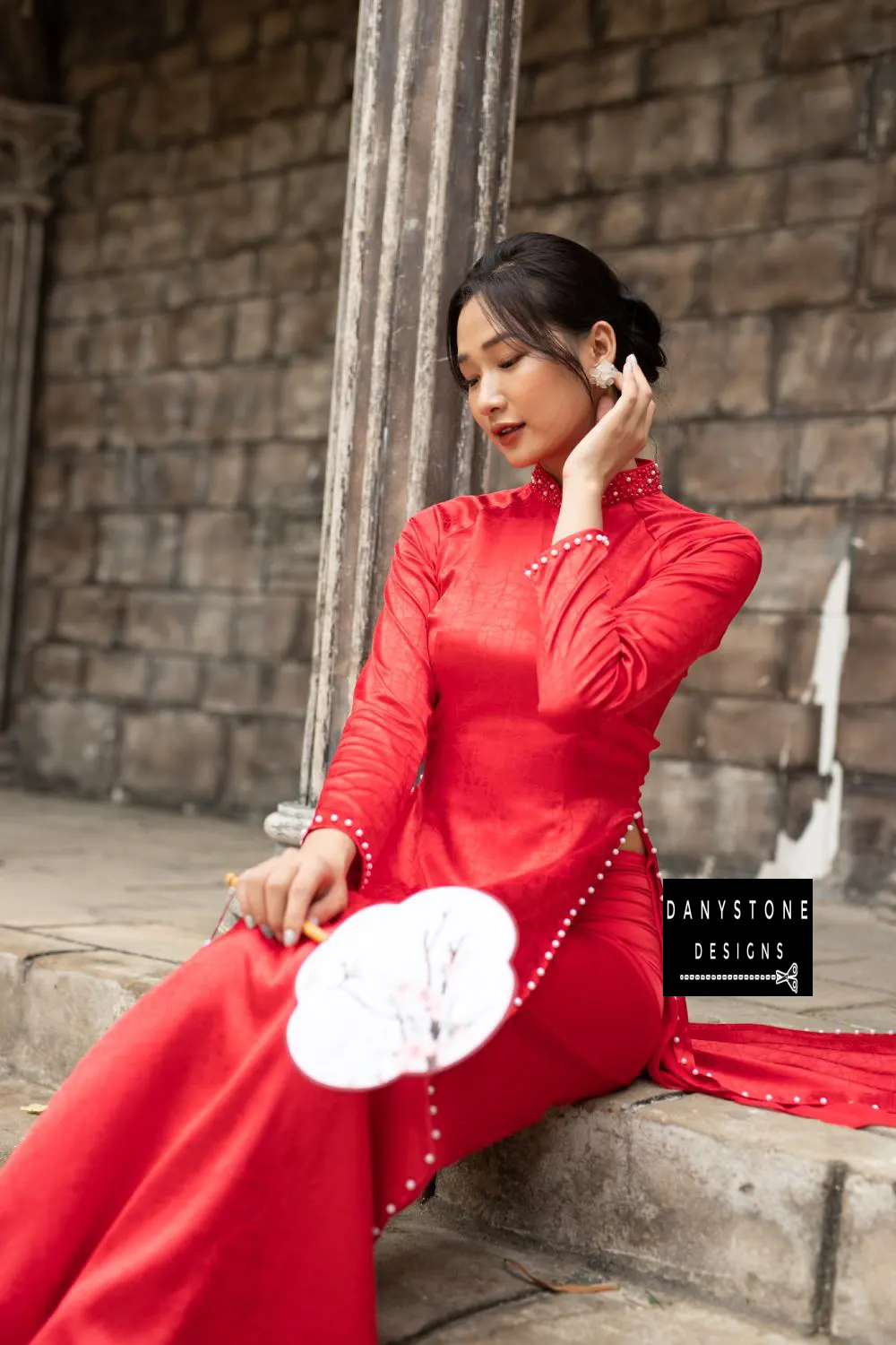 Close-up of a red brocade Áo Dài, showcasing the beaded collar and pearl embellishments.