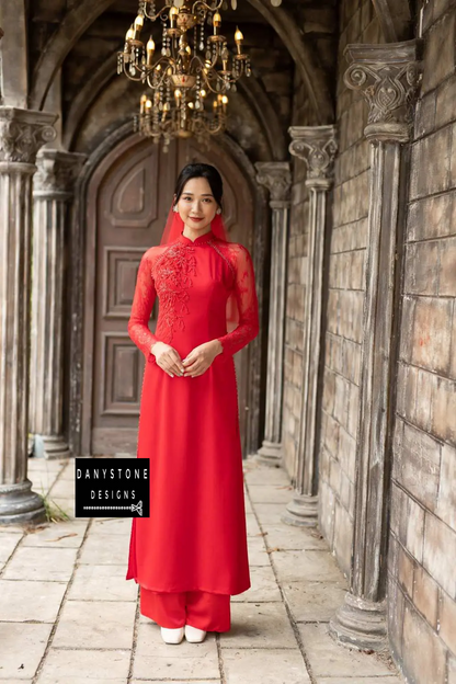 Elegant woman in a red silk bridal Áo Dài with lace and beaded details, smiling and holding her veil.