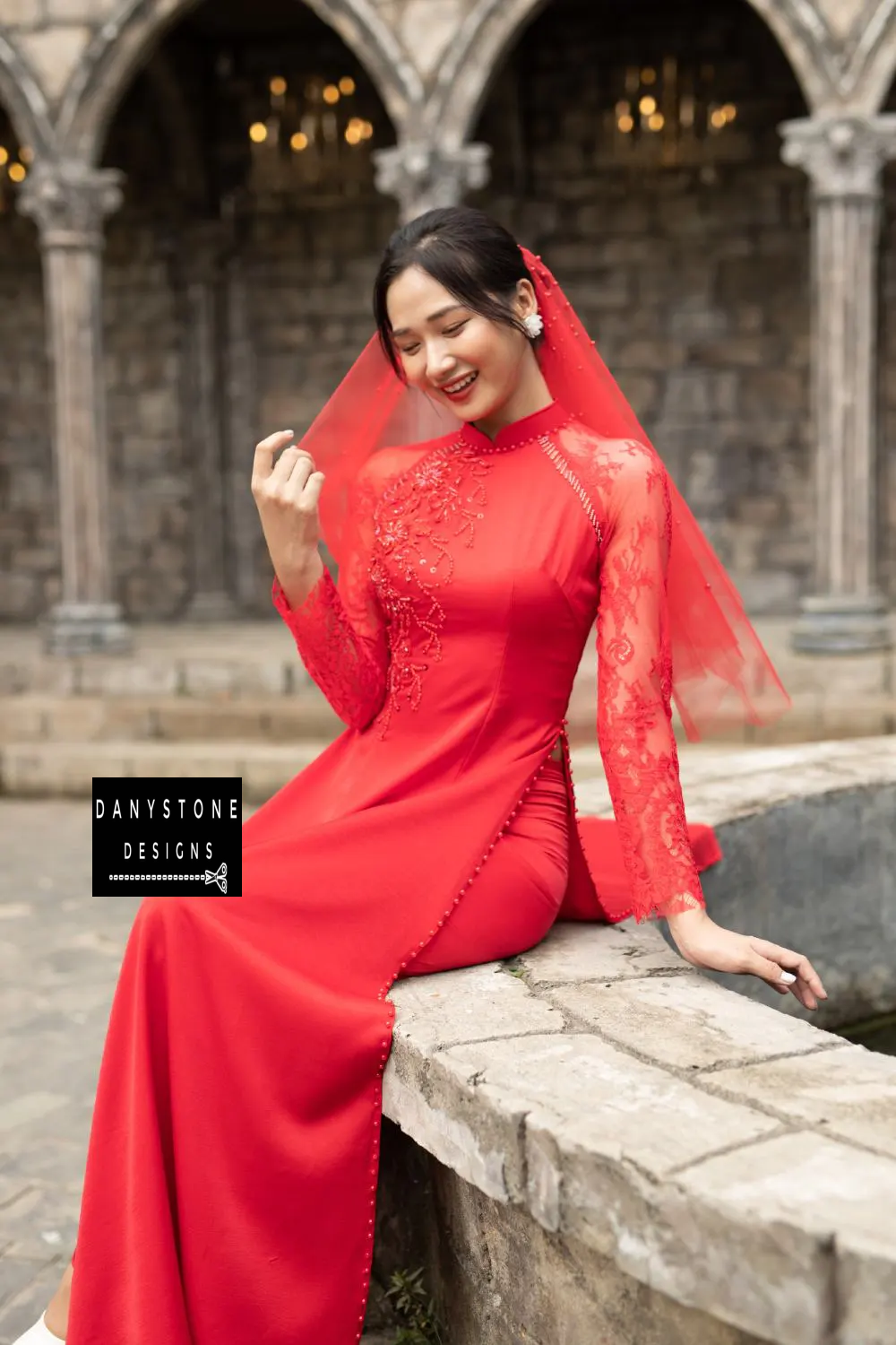 Close-up of a red silk Áo Dài, showcasing the beaded floral details and lace sleeves.