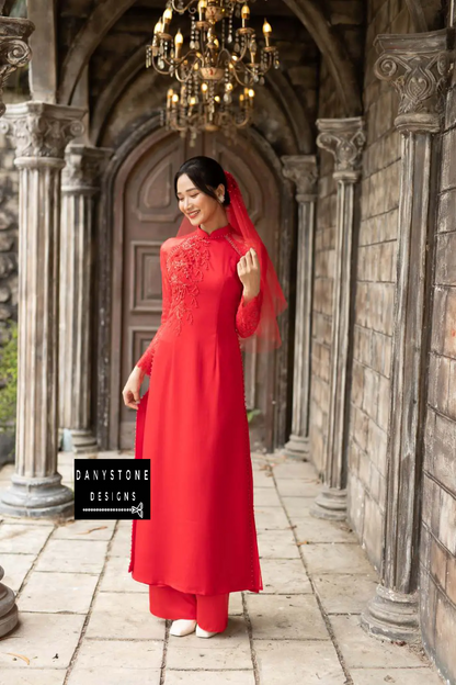 Red silk Áo Dài with luxurious lace and beaded details, worn by a smiling bride.