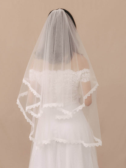 Bride wearing a white wedding dress with a veil against a beige background