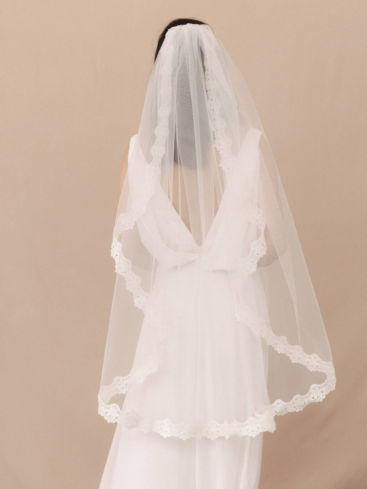 White wedding dress with a veil on a beige background