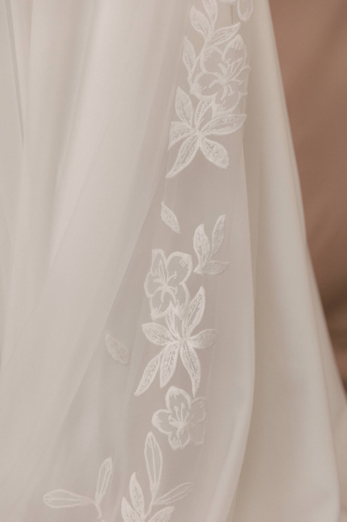 Close-up of a sheer fabric with floral embroidery on a beige background