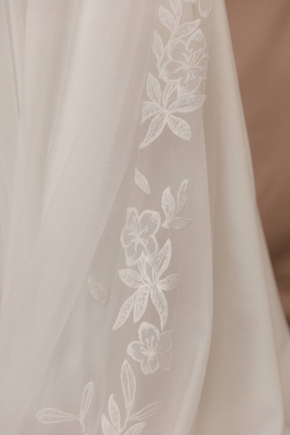 Close-up of a sheer fabric with floral embroidery on a beige background