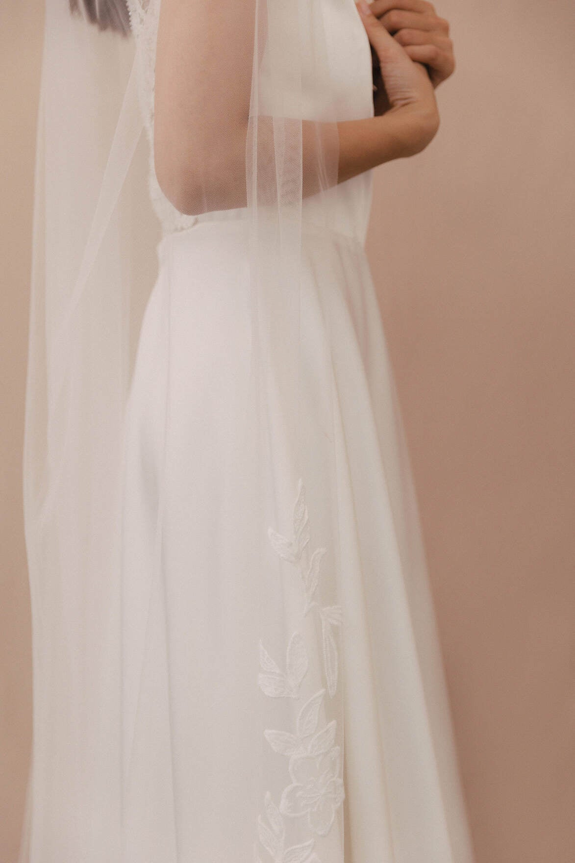 Close-up of a white wedding dress with lace details on a beige background