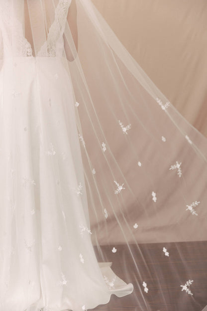 White wedding dress with floral embellishments on a plain background