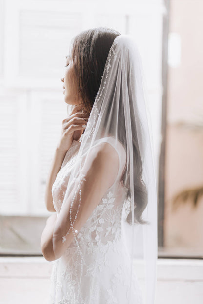 Woman wearing a white wedding dress with a veil in a softly lit room.