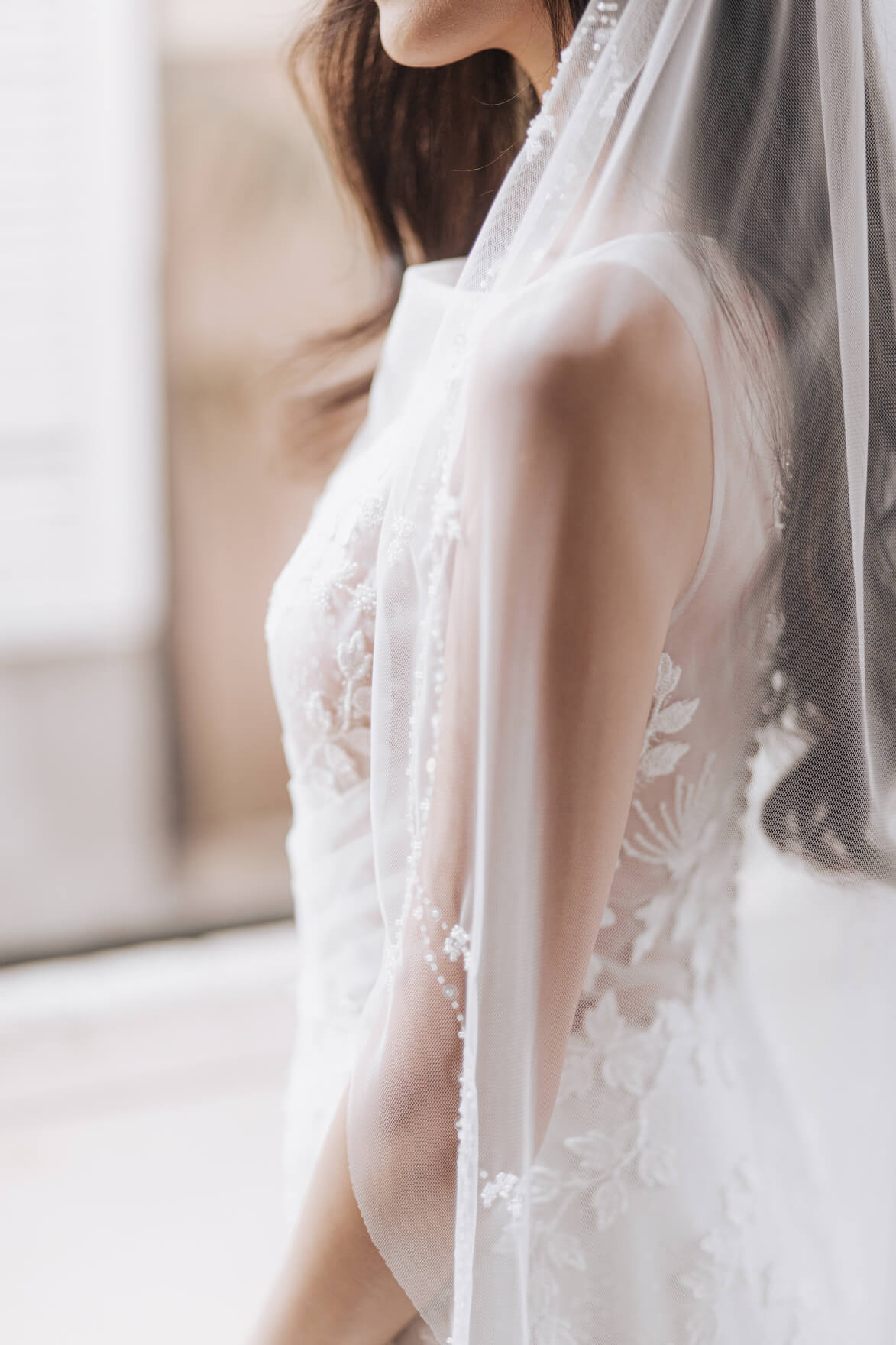 Close-up of a person wearing a white lace dress with a veil.