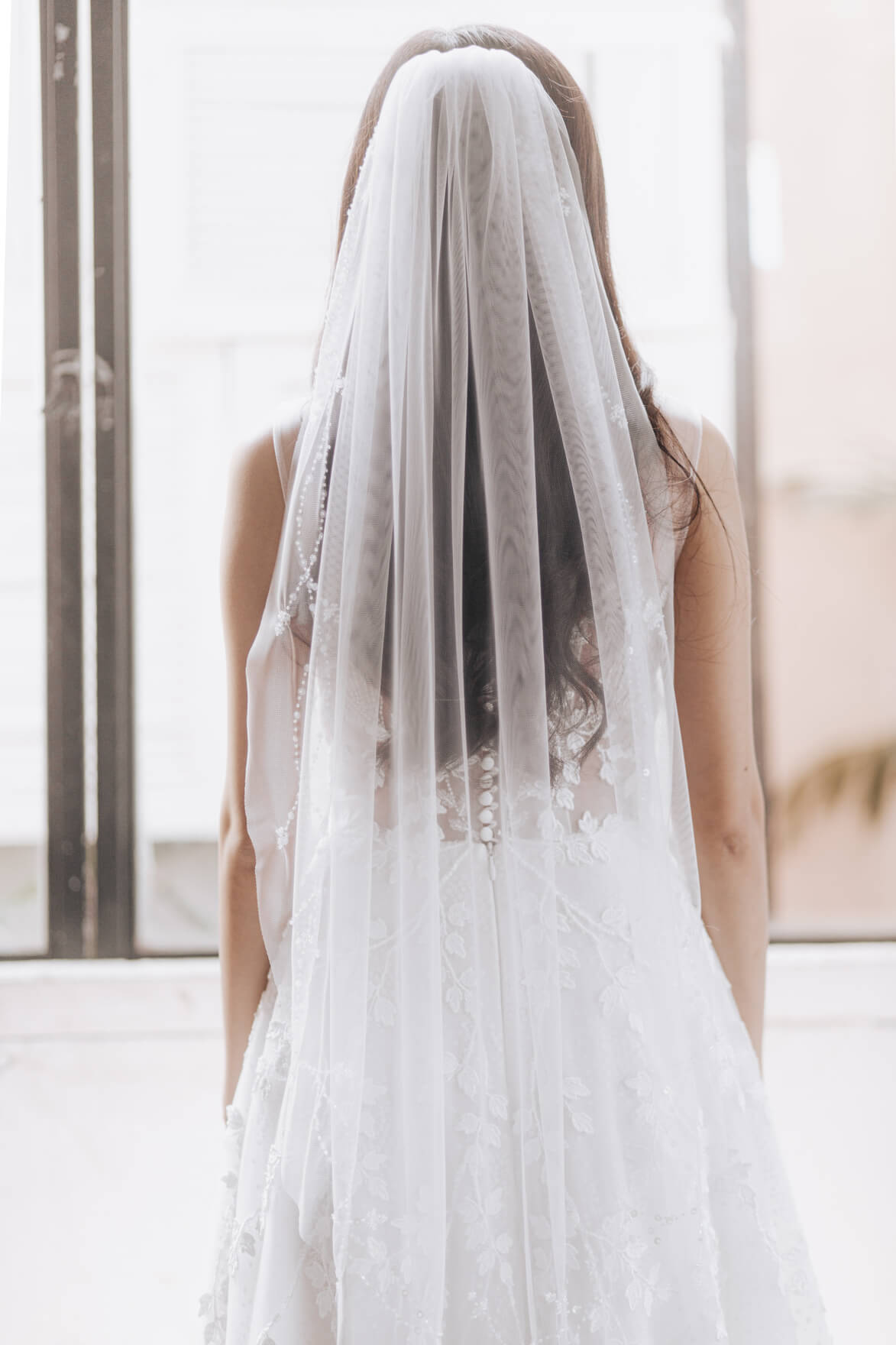 Person wearing a long white veil in an indoor setting