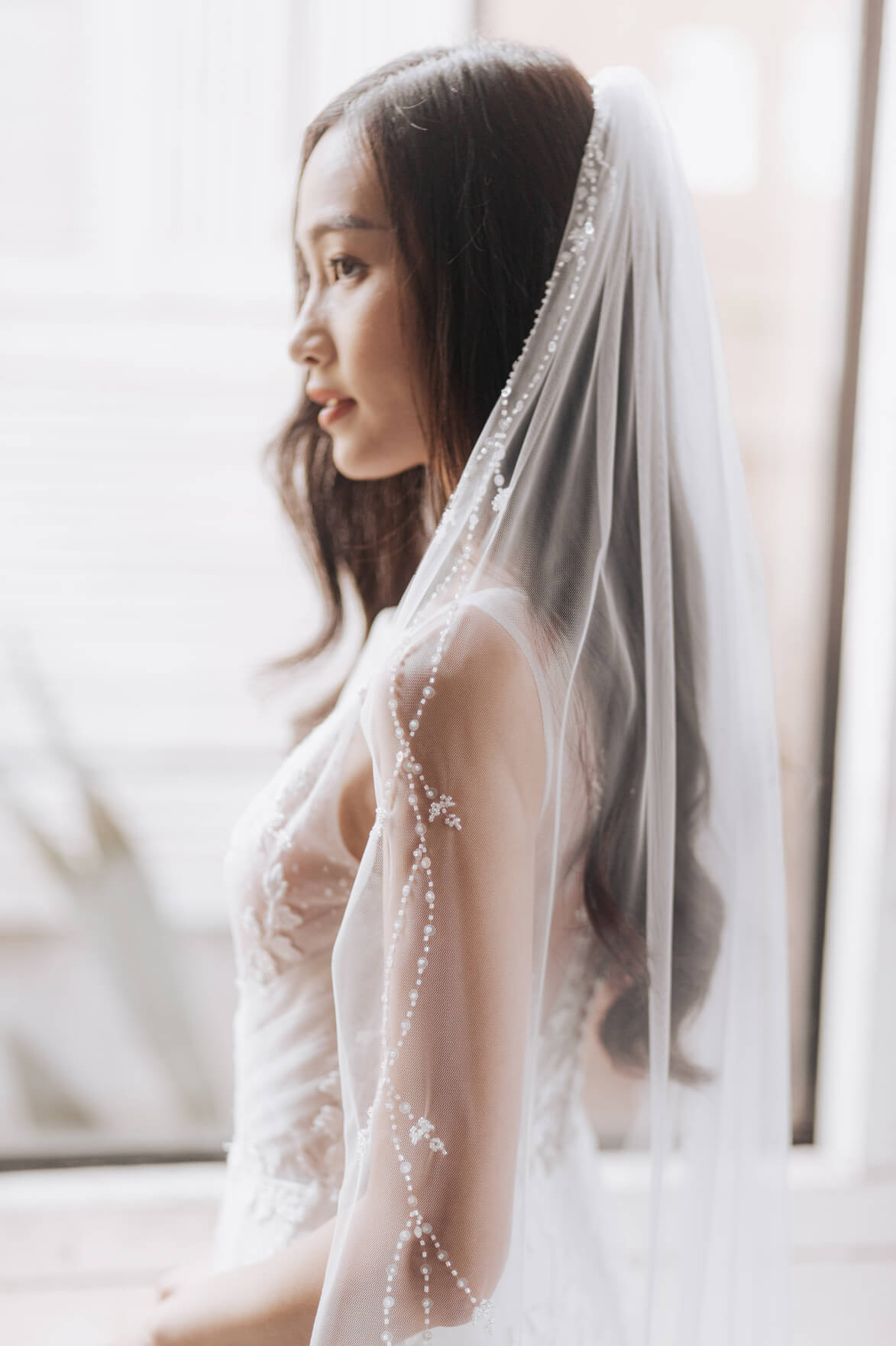Woman wearing a white wedding dress with a veil indoors