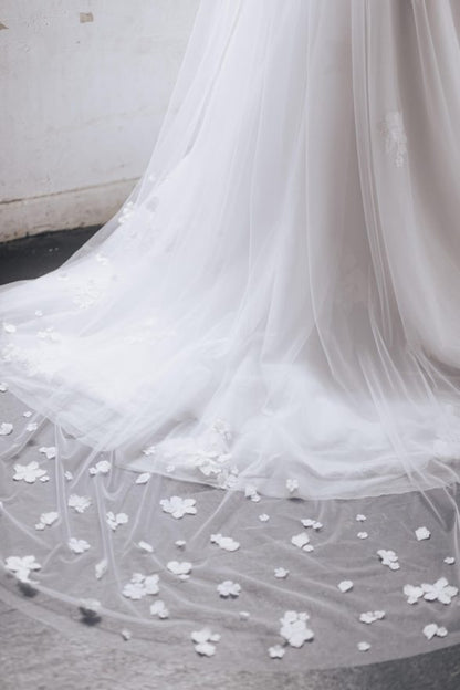 Close-up of a white wedding dress with floral details on a neutral background