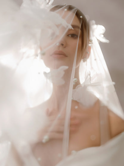 Woman wearing a white wedding dress with a veil and floral headpiece.