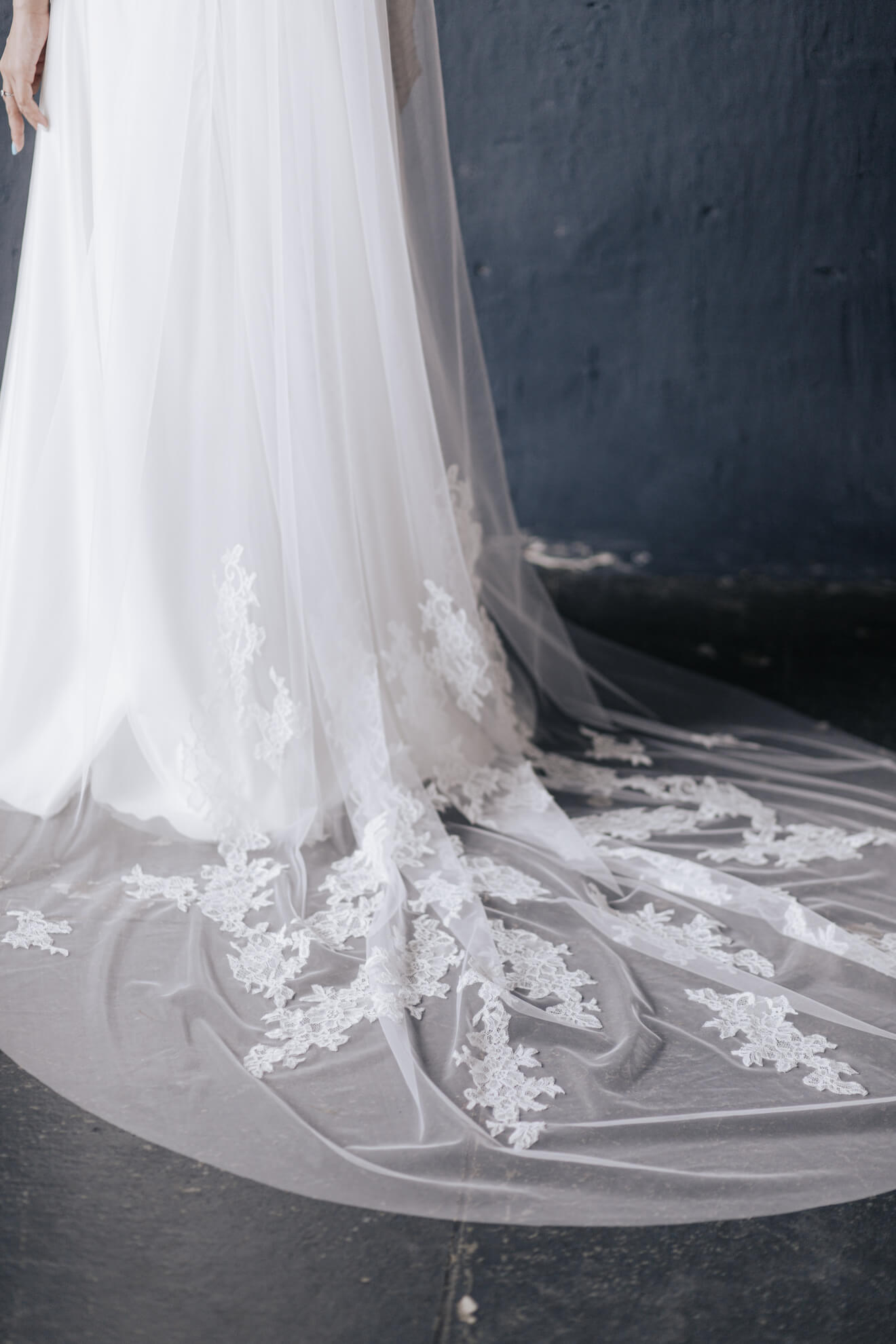 Close-up of a white wedding dress with intricate lace detailing on a dark background
