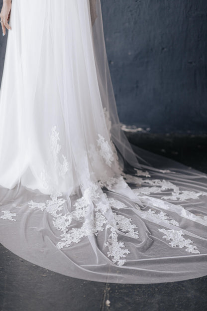 Close-up of a white wedding dress with intricate lace detailing on a dark background