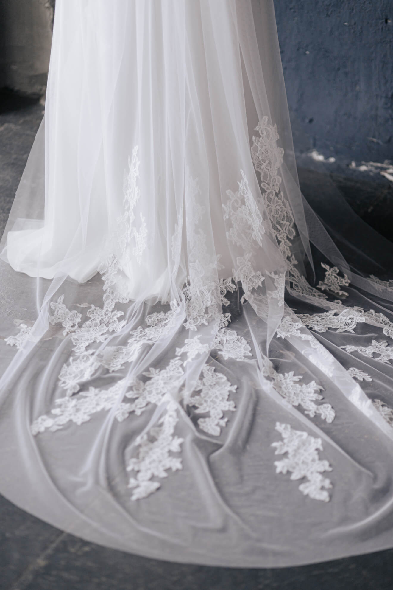 Close-up of a white lace wedding dress with intricate detailing on a dark background