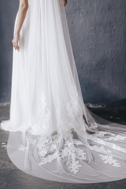 Close-up of a wedding dress with a long, elegant train against a dark background