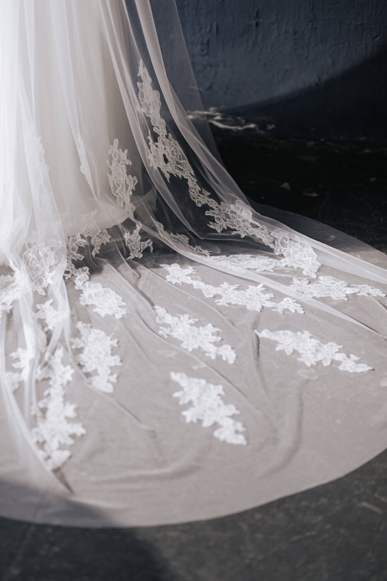 Close-up of a white wedding veil with lace details on a dark background