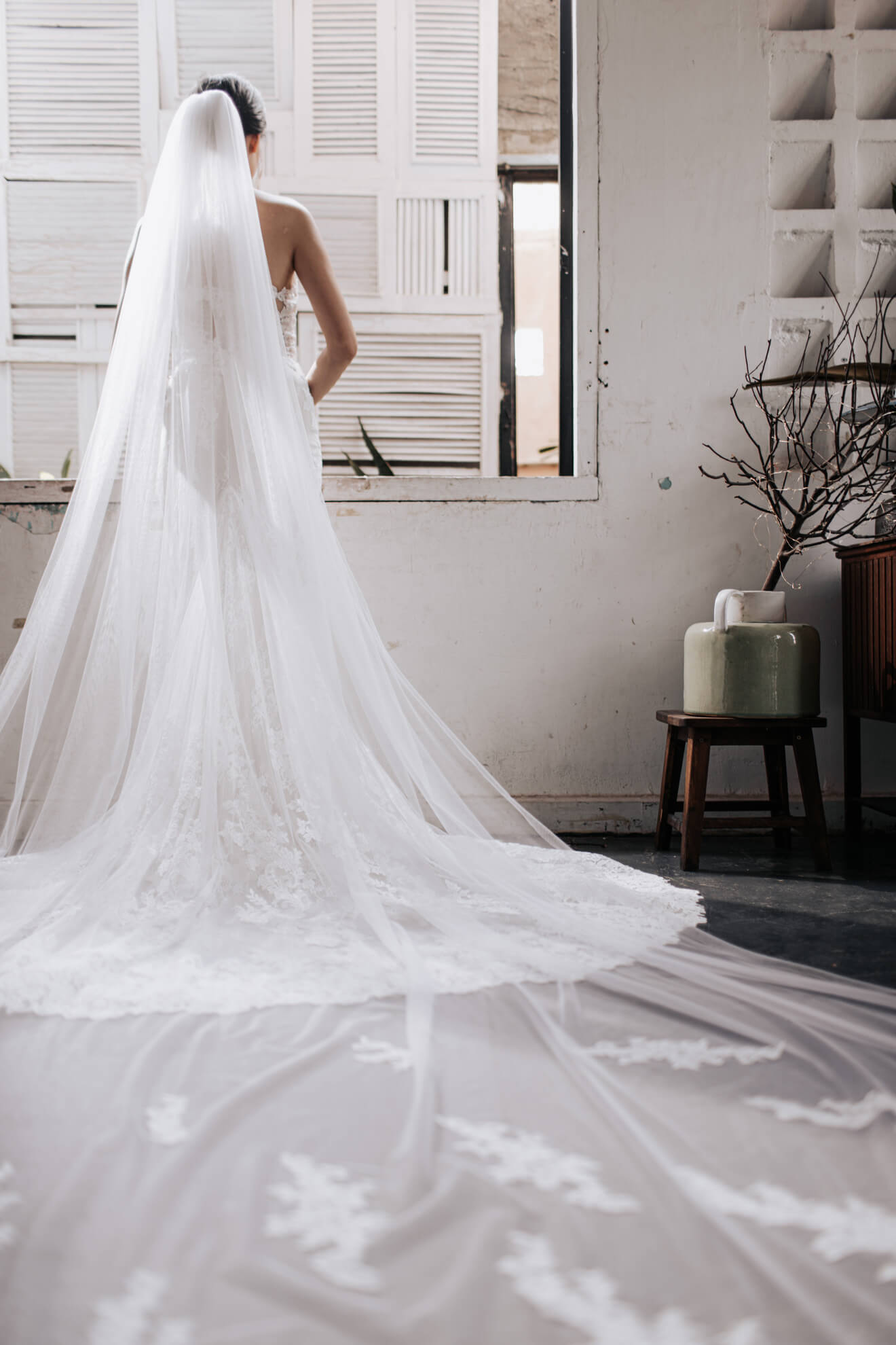 Person wearing a long white wedding veil indoors.