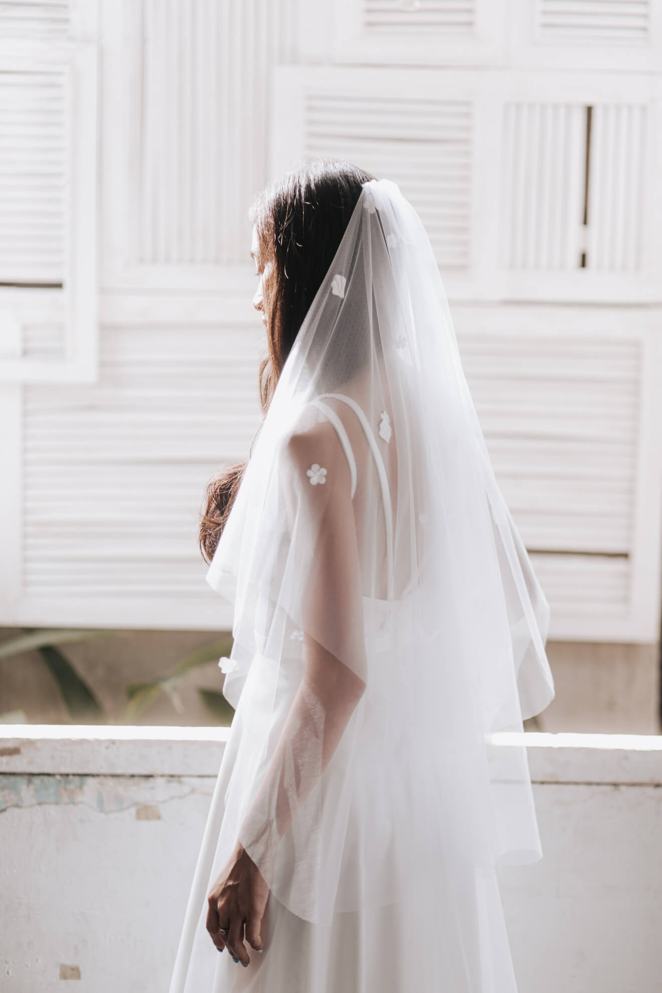 Person wearing a white wedding dress with a veil against a white background