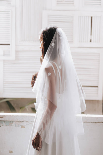 Person wearing a white wedding dress with a veil against a white background