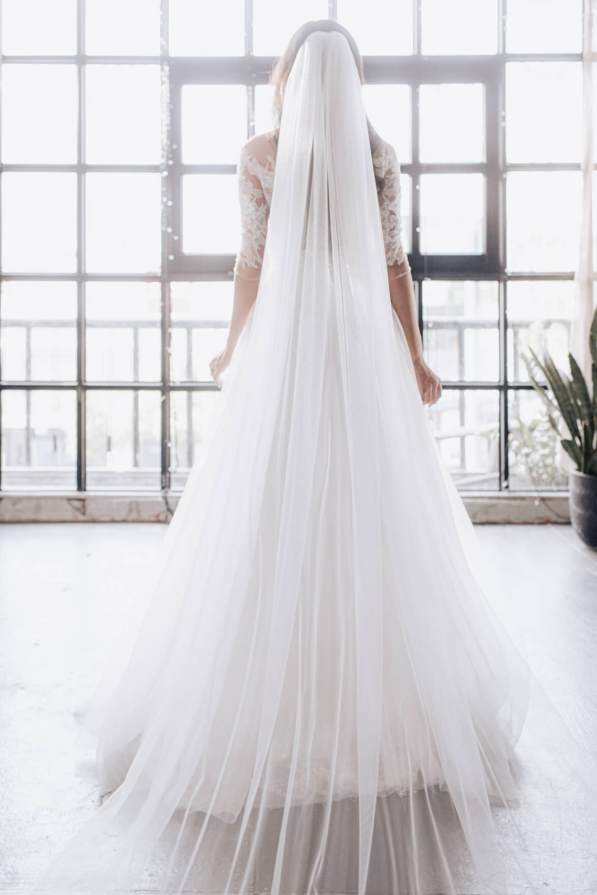 Person wearing a long white wedding dress with a flowing train indoors.
