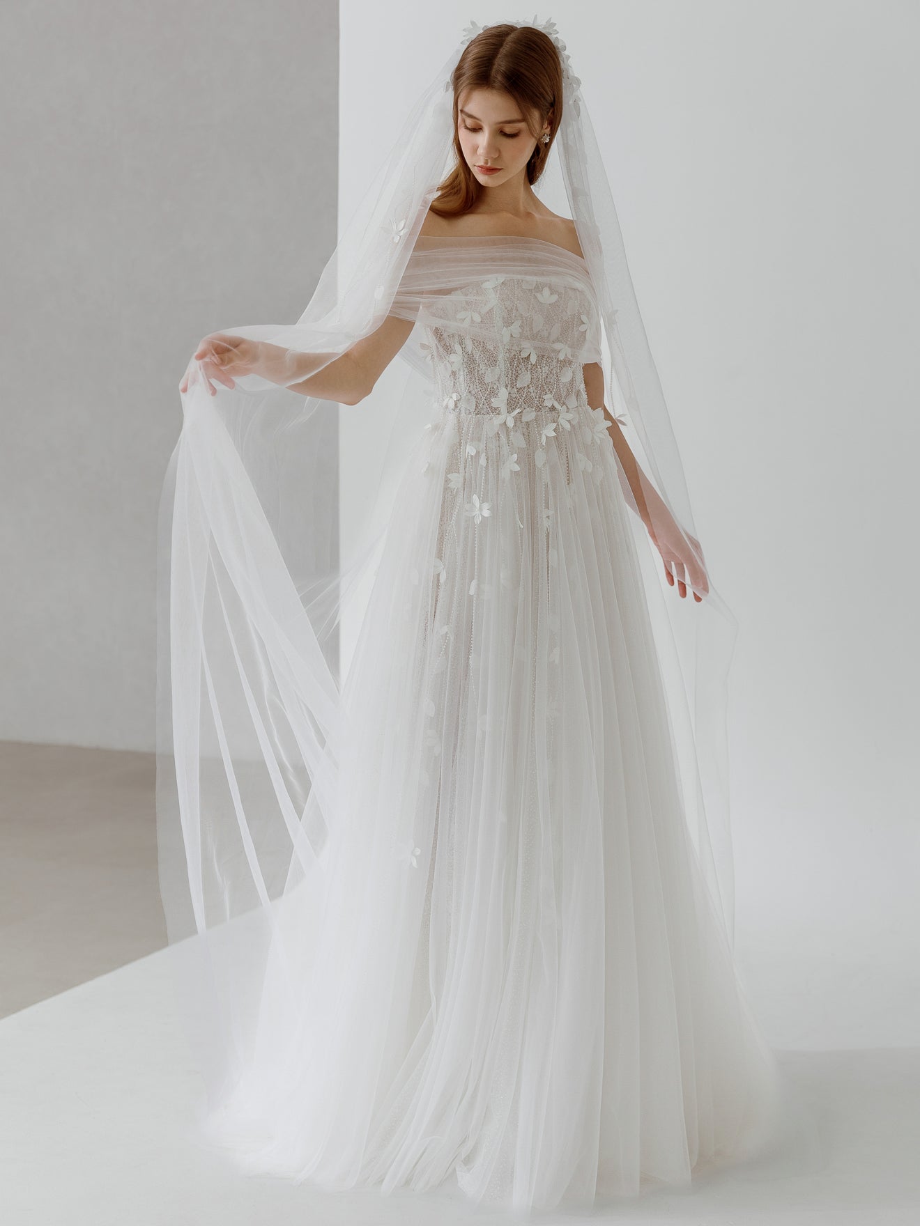 Woman in a wedding dress with a long veil against a plain background