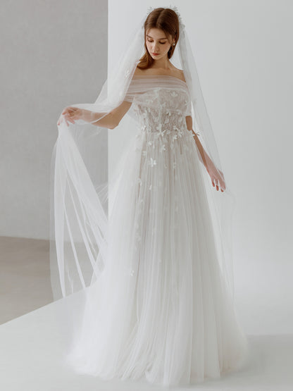 Woman in a wedding dress with a long veil against a plain background