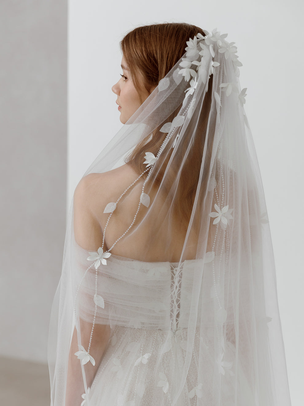 Woman wearing a floral veil against a white background