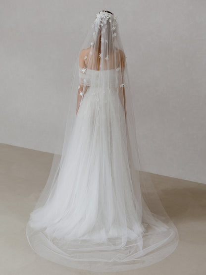 White wedding dress with a long veil on a plain background