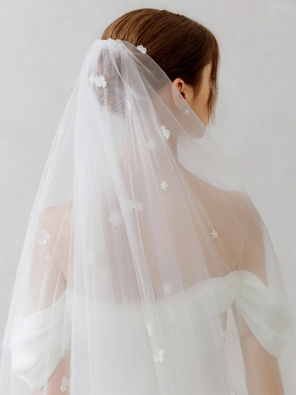 Woman wearing a white wedding dress with a veil against a plain background