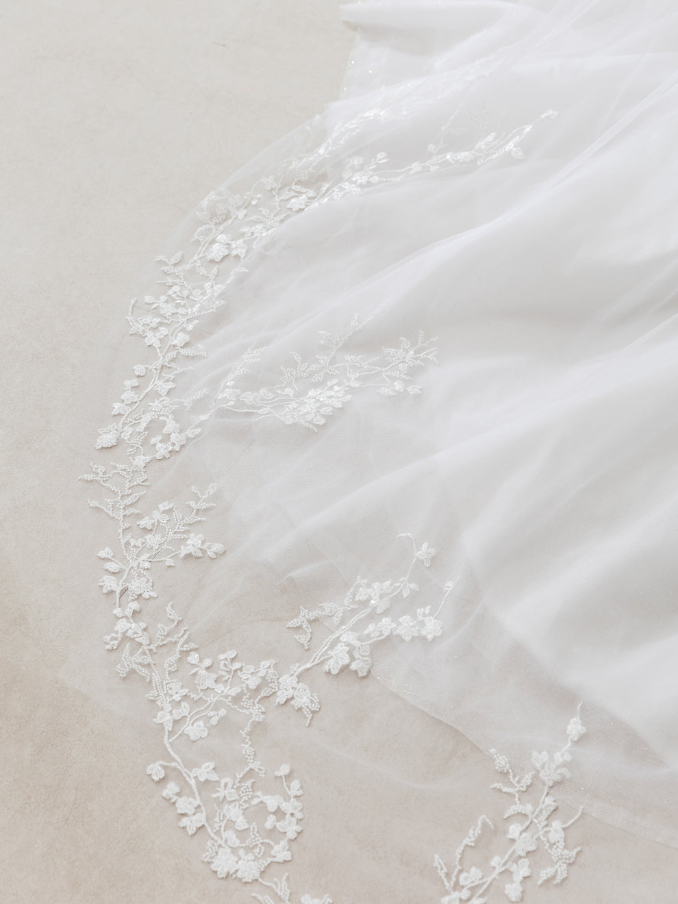 Close-up of a white fabric with delicate lace trim on a neutral background