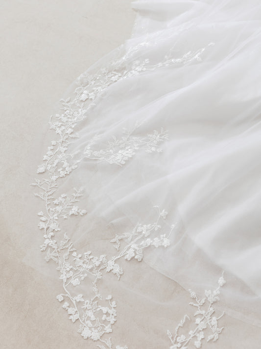 Close-up of a white fabric with delicate lace trim on a neutral background