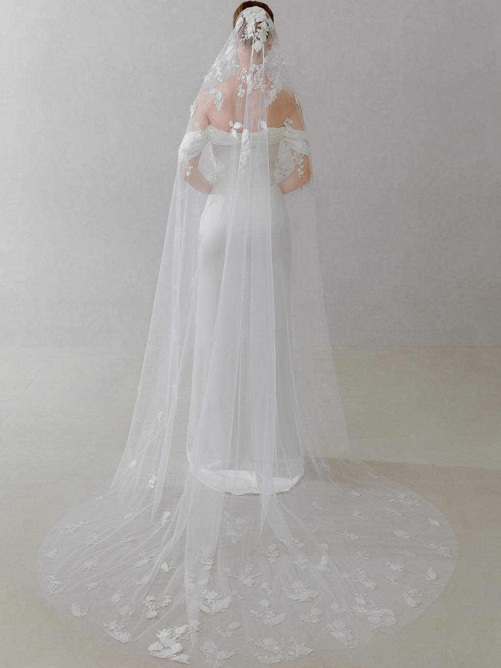 White wedding dress with a long veil on a plain background