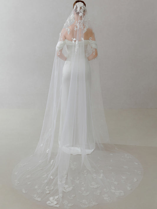 White wedding dress with a long veil on a plain background