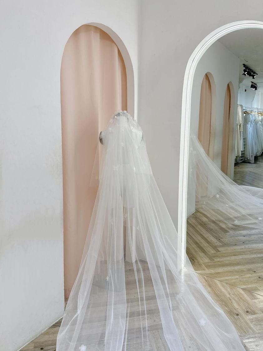 Mannequin draped in Ethereal Chapel-Length Veil with delicate floral embellishments, displayed in a bridal boutique.