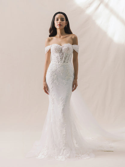 Woman wearing a white off-shoulder lace wedding dress against a neutral background
