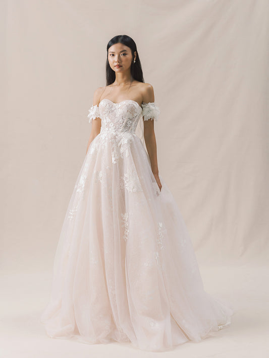 Woman wearing a white lace wedding dress against a plain background