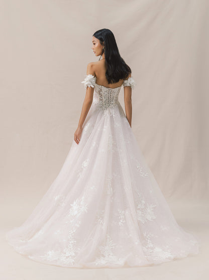 Woman wearing a white wedding dress with floral details against a beige background