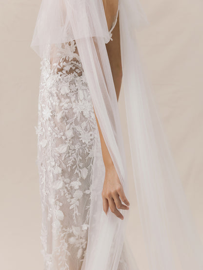 White lace wedding dress with a sheer overlay on a neutral background